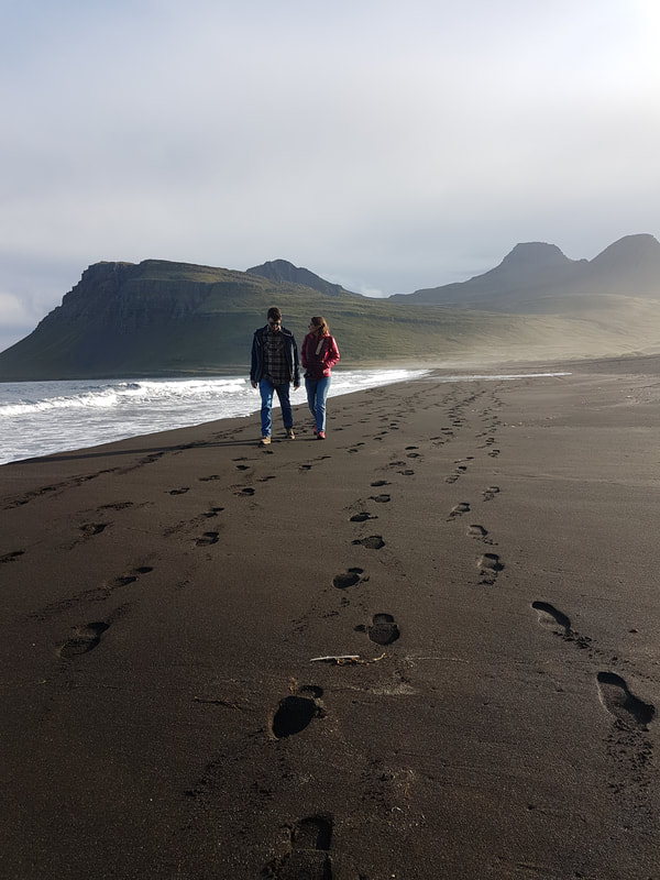 Maður og kona ganga eftir ströndinni í Vöðlavík. 