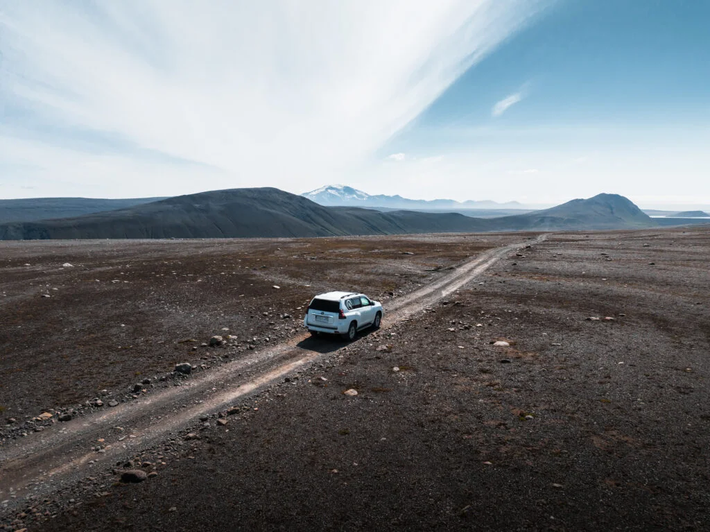 A four-wheel-drive vehicle on a gravel road in the Icelandic highlands