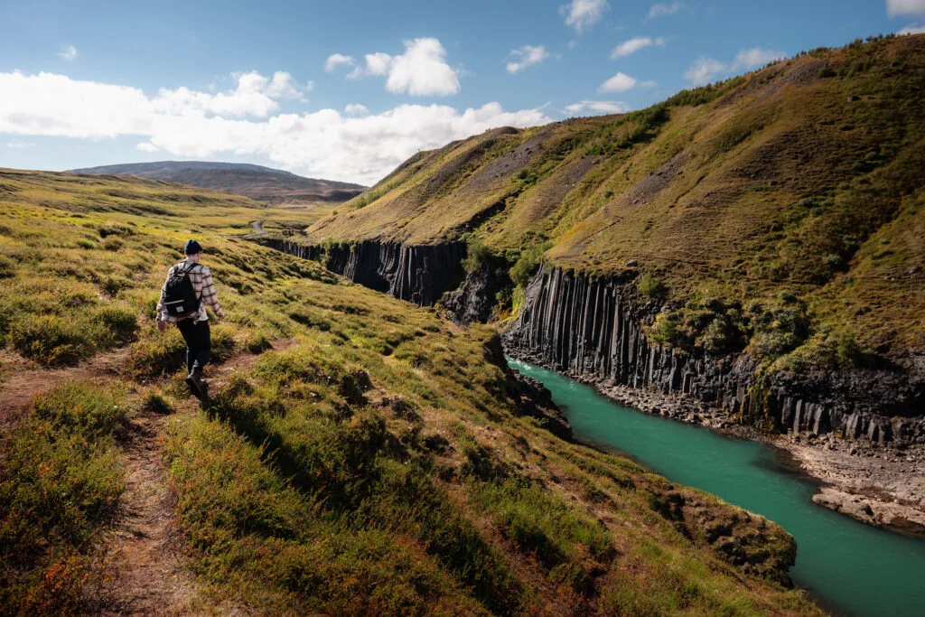 A hiker following the grassy trail above Stuðlagil Canyon