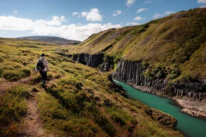 A hiker following the grassy trail above Stuðlagil Canyon