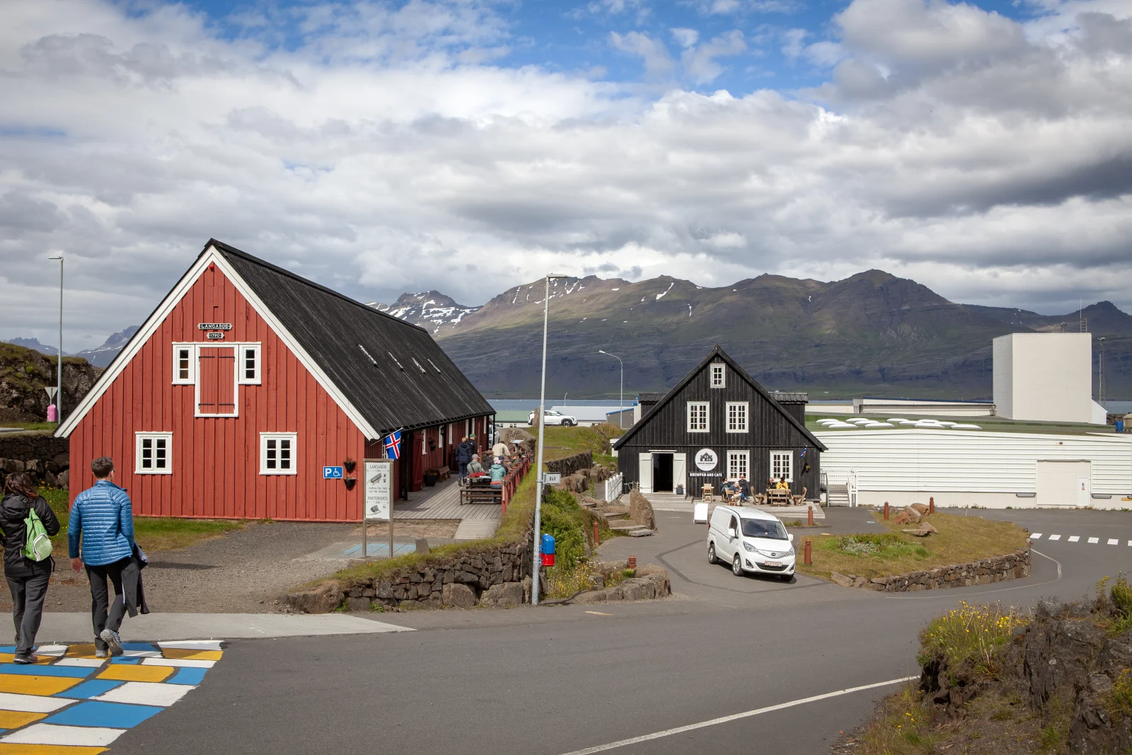 Red and black buildings in Djúpivogur with mountains across the water