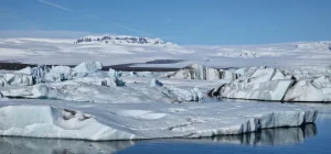 Layered glacial icebergs with snow-covered mountains behind them