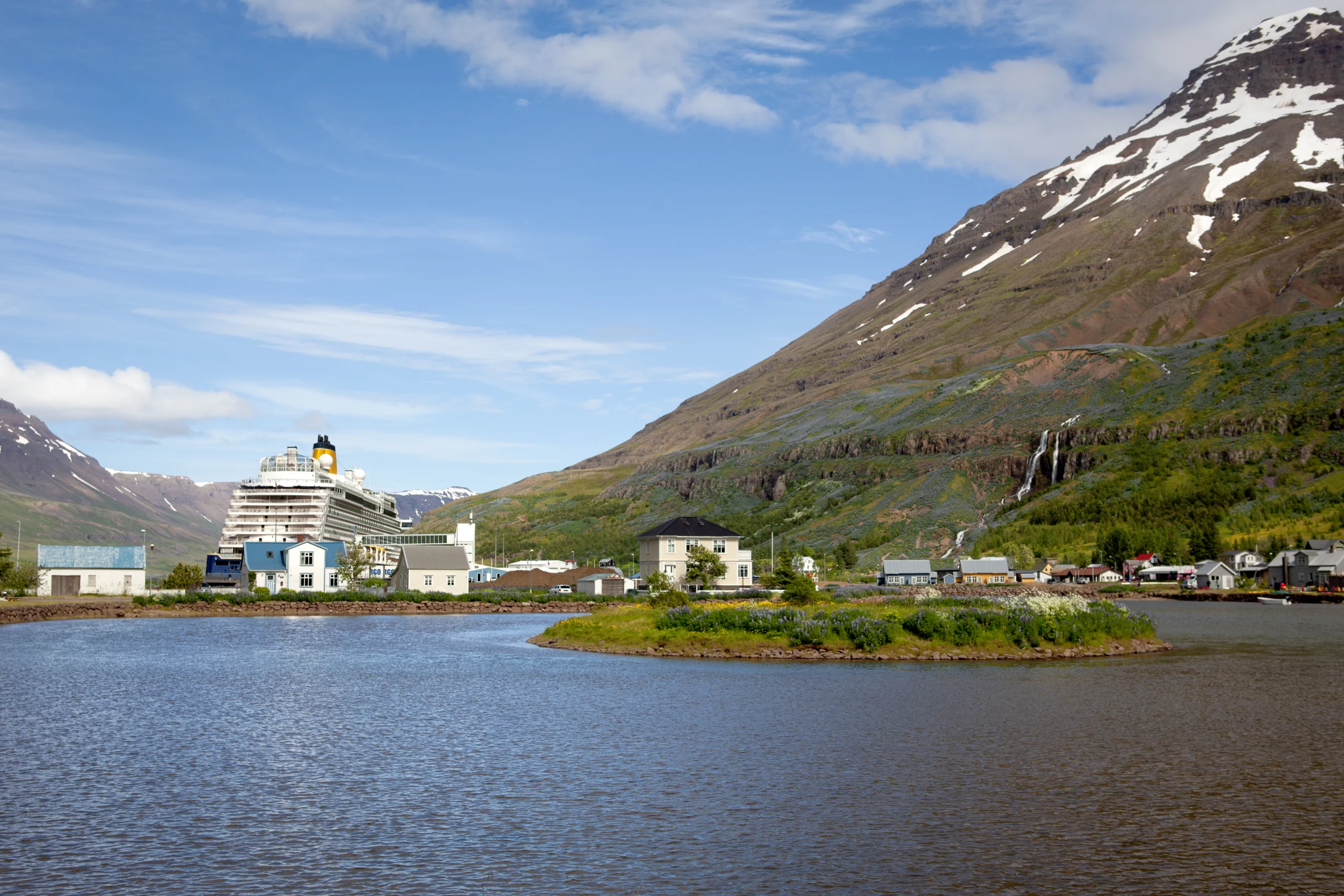 Seyðisfjörður harbour with a visiting ship, waterfront houses and mountain waterfalls